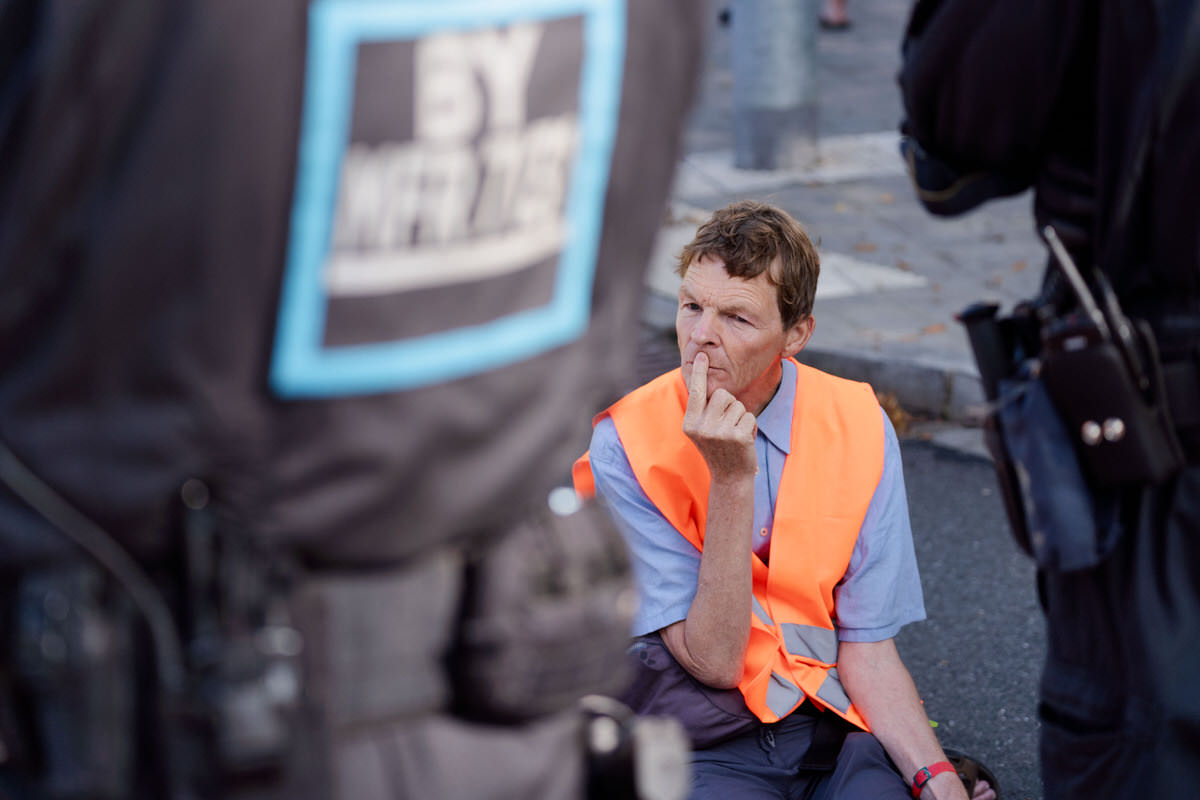 Aktivist der Letzten Generation sitzt auf der Straße